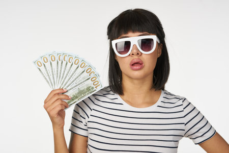 woman in a striped t-shirt wearing glasses with money in hands wealth finance