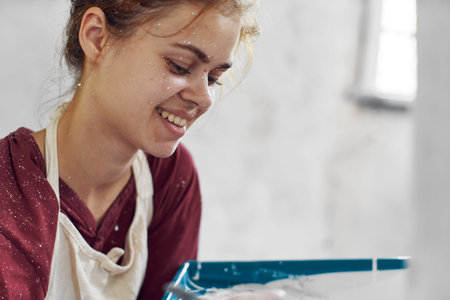 cheerful woman paints a room in a house renovation interior