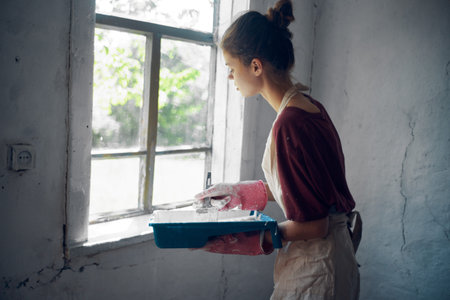 woman painter paints window with brush renovation interior decoration