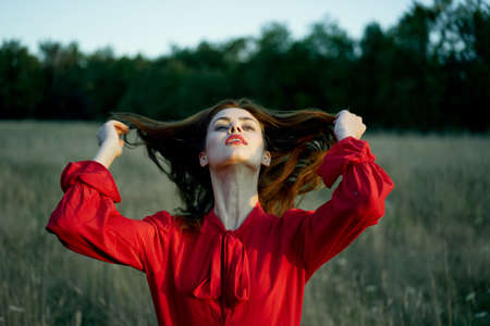 cute red-haired woman in red dress in field nature summerの写真素材