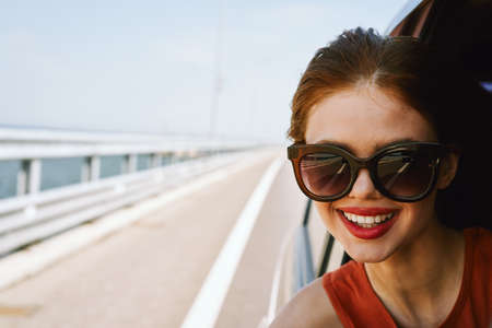 a woman is driving in a car on the road and looking out of the windowの写真素材