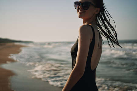 woman in black swimsuit walking on the beach ocean summerの写真素材