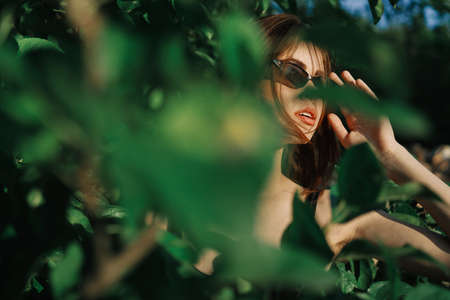 pretty woman wearing sunglasses green leaves posing summerの写真素材