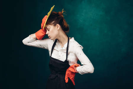 housewife in a black apron with a rag in her hands cleaningの写真素材