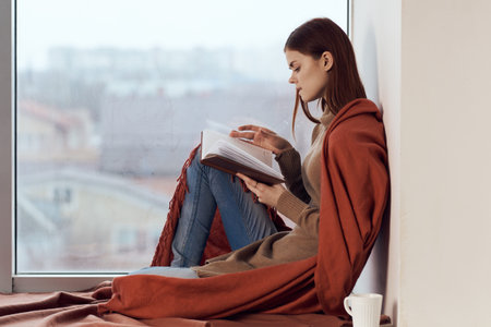 woman near the window with a plaid cup of hot drink rest