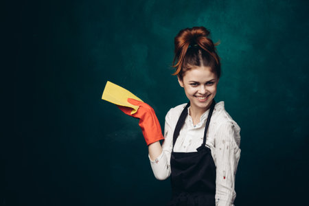 woman with rubber gloves in apron cleaning houseworkの写真素材