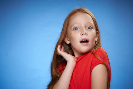 cheerful cute red-haired girl childhood blue backgroundの写真素材