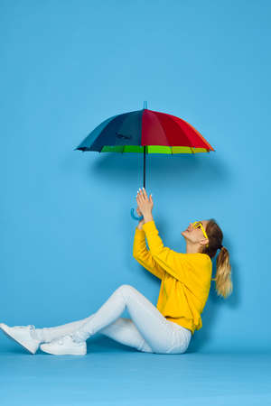 woman with multicolored umbrella in yellow sweater posing rainbow colorsの写真素材
