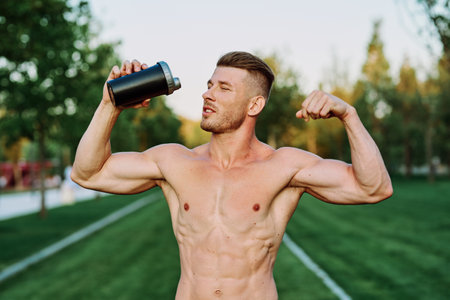 athletic man with pumped up muscular body in the park exercise workout motivationの写真素材