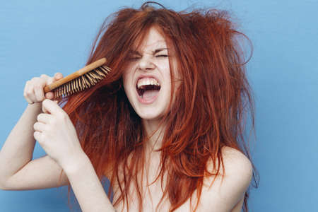 woman with red hair comb care blue backgroundの写真素材