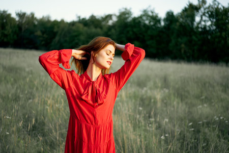 pretty woman in red dress in field nature posing landscapeの写真素材