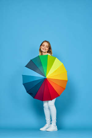 fashionable woman with umbrella rainbow colors posing blue backgroundの写真素材