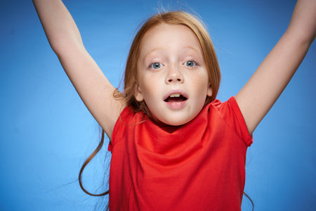 cute red-haired girl in red t-shirt emotions blue backgroundの写真素材