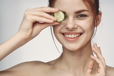 attractive woman with bare shoulders cucumber skin care healthの写真素材