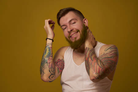 macho man in white t-shirt tattoos on his arms posing isolated backgroundの写真素材