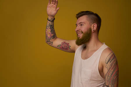 macho man in white t-shirt tattoos on his arms posing isolated backgroundの写真素材