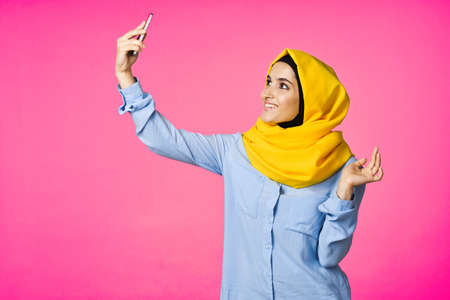 cheerful woman in a yellow hijab with a phone in her hands communication technologyの写真素材