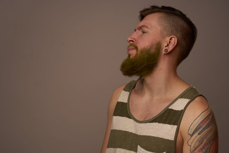 fashionable man with tattoos on his arms stylish hairstyle self-confidence studio