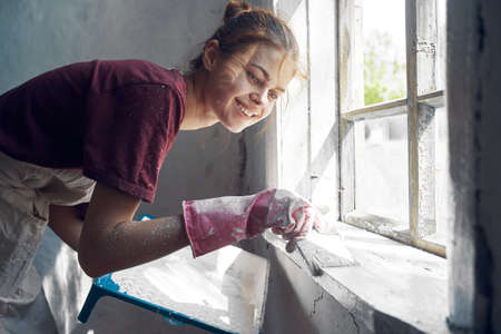 woman with brush paints window sill at home near window interior renovationの写真素材