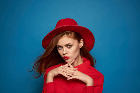 beautiful woman wearing a red hat cosmetics posing blue backgroundの写真素材