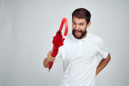 man with red umbrella in hands protection from rain dispensing light backgroundの写真素材