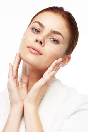 Woman in white robe posing fun skin care patches on faceの写真素材