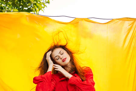 pretty woman in red dress gesturing with her hands nature yellow backgroundの写真素材