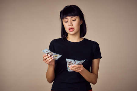 woman in a black t-shirt a wad of money dollars payment beige backgroundの写真素材