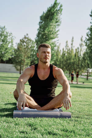 sporty man sitting on the lawn in the park trainingの写真素材