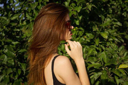 attractive woman posing on the background of green leaves natureの写真素材