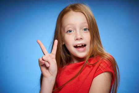 cute red-haired girl in red t-shirt emotions blue backgroundの写真素材