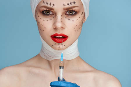female patient posing in blue gloves red lips surgery facial rejuvenation close-upの写真素材