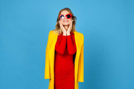 woman in yellow jacket posing makeup fashion blue backgroundの写真素材