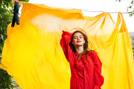 women near yellow fabric in nature in red dress fashionの写真素材