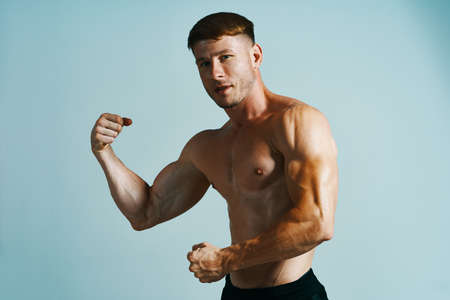 bodybuilder with muscular body posing press blue backgroundの写真素材