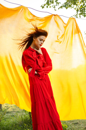 pretty woman in red dress yellow fabric on nature backgroundの写真素材