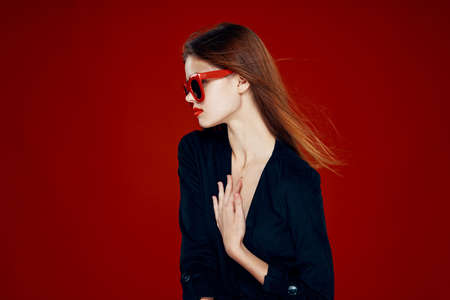 pretty woman wearing sunglasses fashion posing hairstyle red backgroundの写真素材