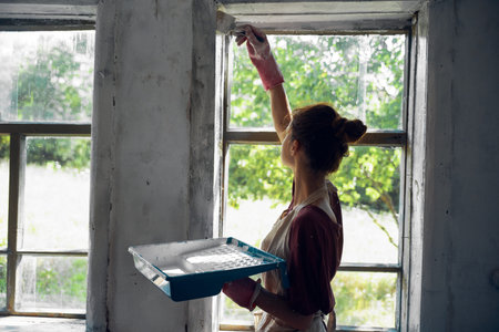 woman paints windows in the house interior room renovationの写真素材