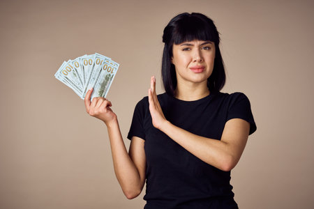 woman in a black t-shirt a wad of money dollars payment beige background