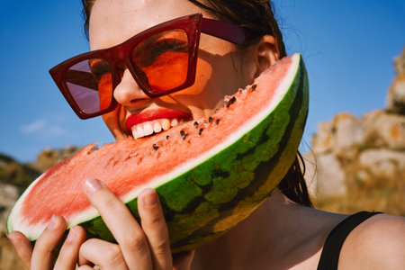 Cheerful woman eating watermelon nature summer vacationの写真素材