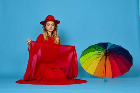 woman in red dress multicolored umbrella blue backgroundの写真素材