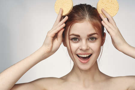 woman yellow sponge clean skin hygiene light backgroundの写真素材