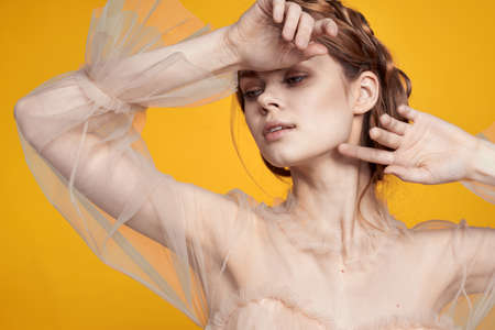 pretty woman gesture hands cosmetics fashion hairstyle posing yellow backgroundの写真素材