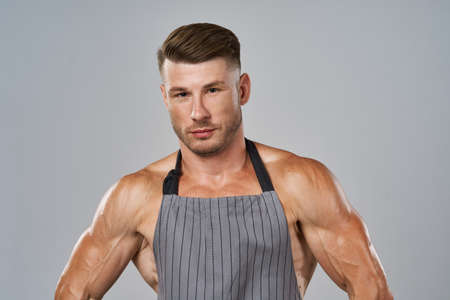 pumped up man in apron wearing rubber gloves posing cleanerの写真素材