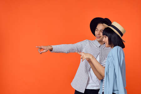 man and woman in hats posing fashion orange backgroundの写真素材