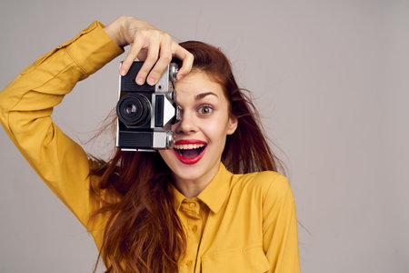 pretty woman photographer with camera in yellow shirt on blue backgroundの写真素材