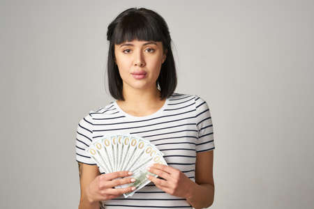 woman in a striped t-shirt wearing glasses with money in hands wealth financeの写真素材