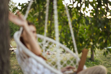 woman with laptop outdoors resting in hammock internetの写真素材