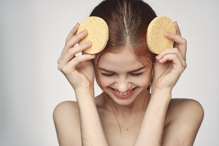 woman yellow sponge clean skin hygiene light backgroundの写真素材