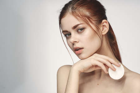 woman with bare shoulders cotton pad clean skin light backgroundの写真素材